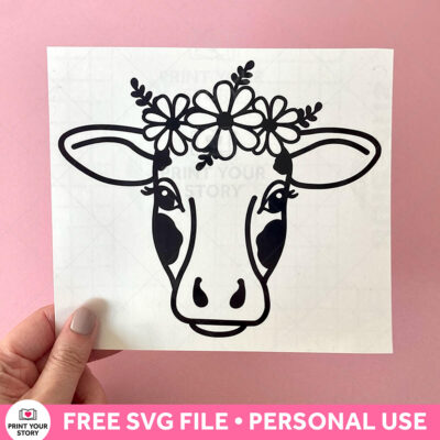 Black cow face SVG with flower crown shown on a white square sheet against a pink background