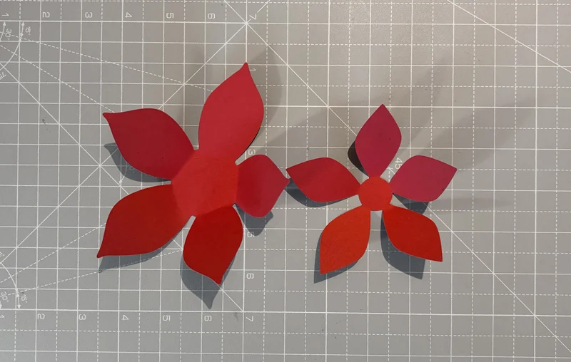 Red paper poinsettia petal layers on a cutting mat