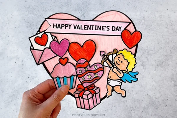 Hand holding a colored Valentine’s Day paper craft with hearts, Cupid, cupcake, gift, and banner