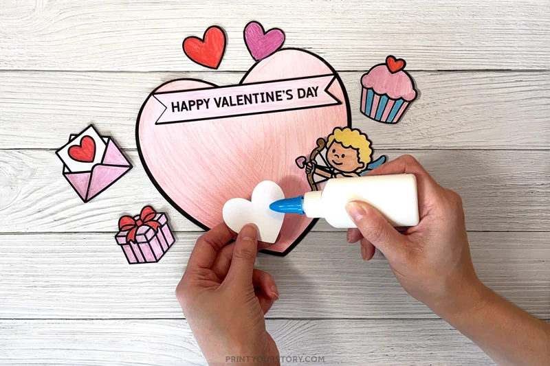 Child gluing a paper flower onto a handmade Valentine’s Day coloring card craft
