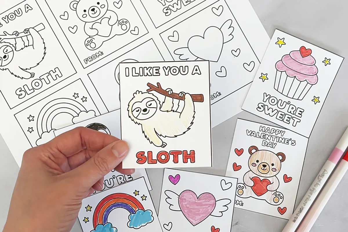 Printable Valentine coloring cards with a colored sloth card held over uncolored card sheets