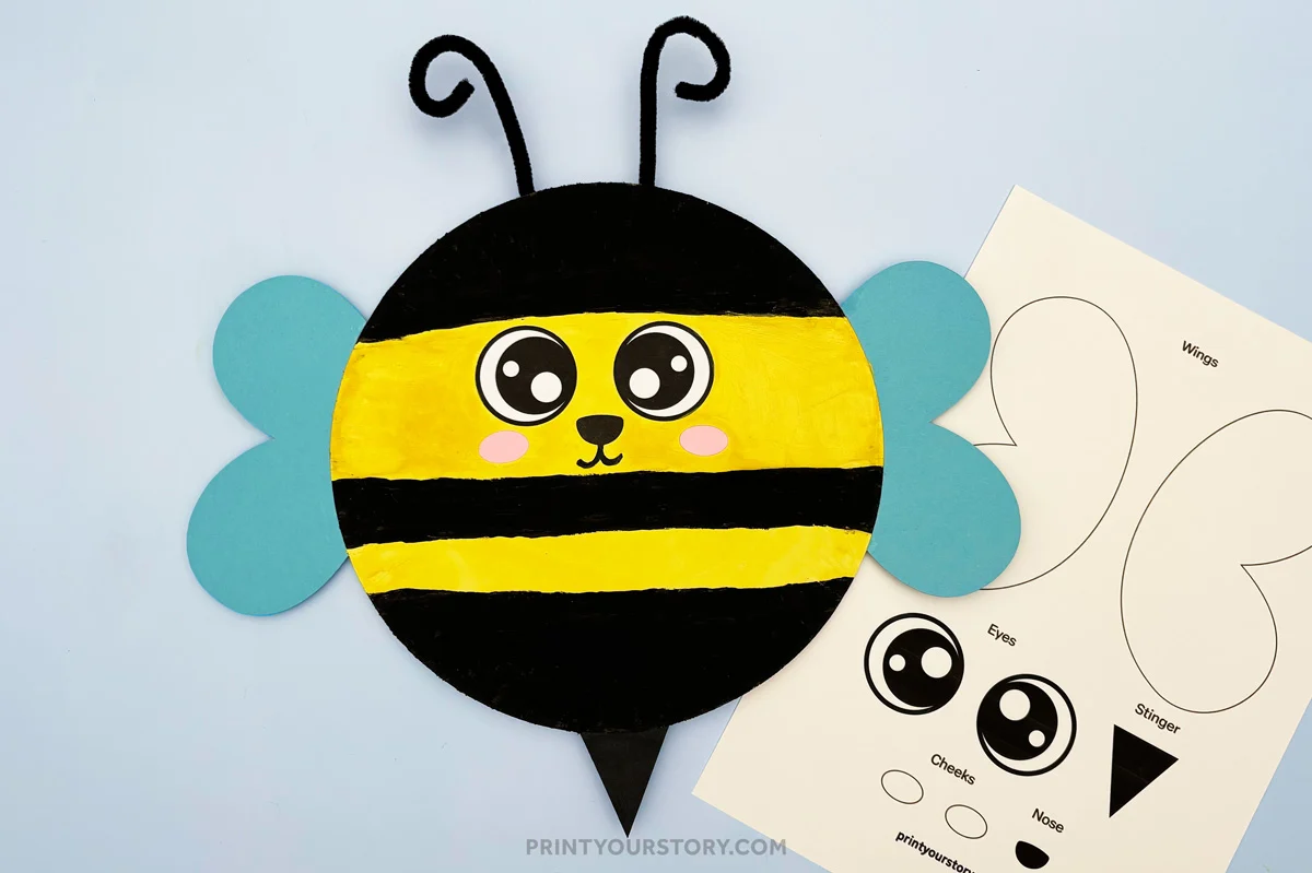 Finished paper plate bee craft on a blue background next to a paper bee template