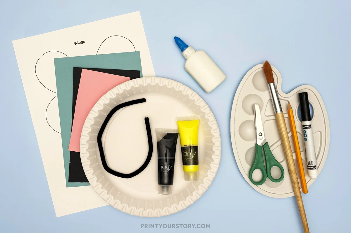 Materials for a bumble bee paper plate craft with a plate, paint, paper, glue, brushes
