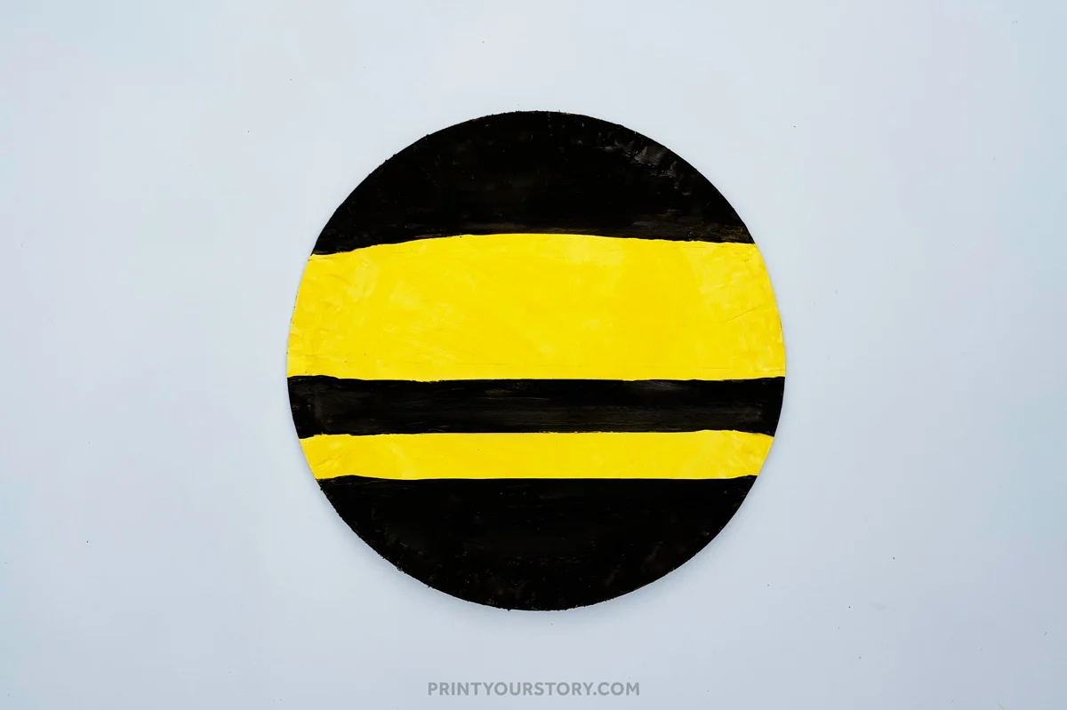 Paper plate painted with black and yellow stripes for a bumble bee craft