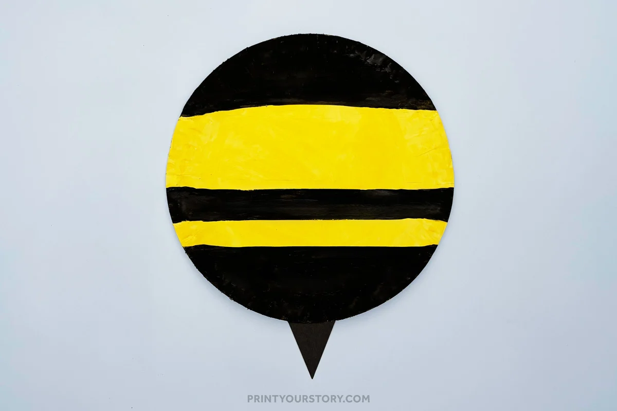 Painted paper plate bumble bee body with yellow and black stripes and a stinger
