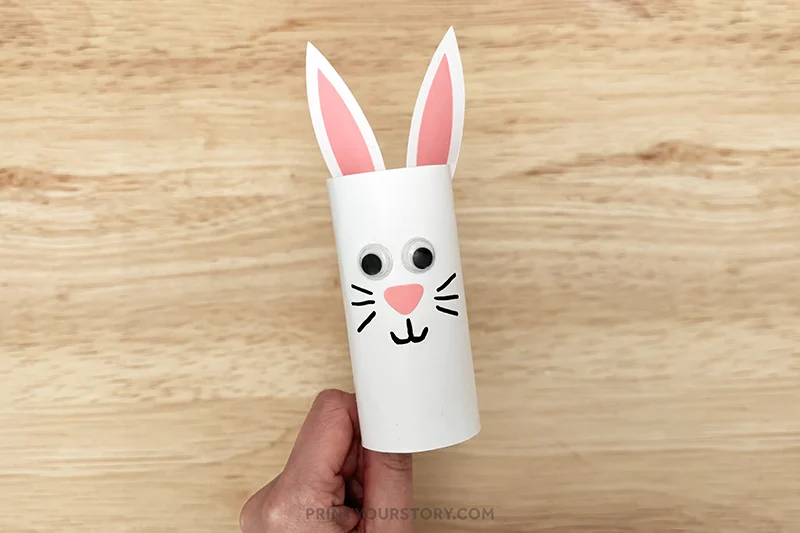 Toilet paper roll bunny craft with paper ears, googly eyes, and drawn whiskers