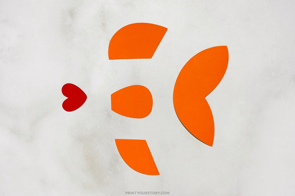 Orange and red paper pieces cut into fins and a heart-shaped mouth for a paper plate fish craft