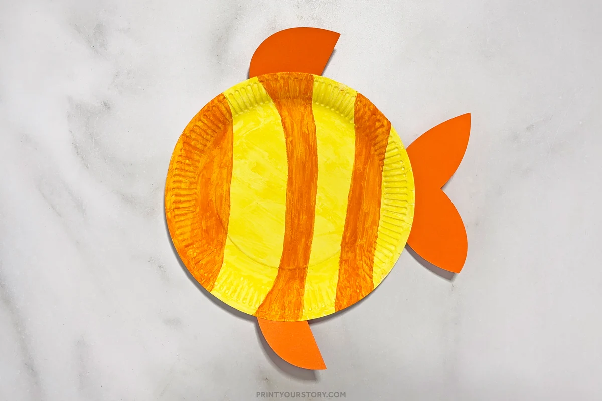 Paper plate painted yellow with orange stripes and several orange fins attached for a paper plate fish crafts