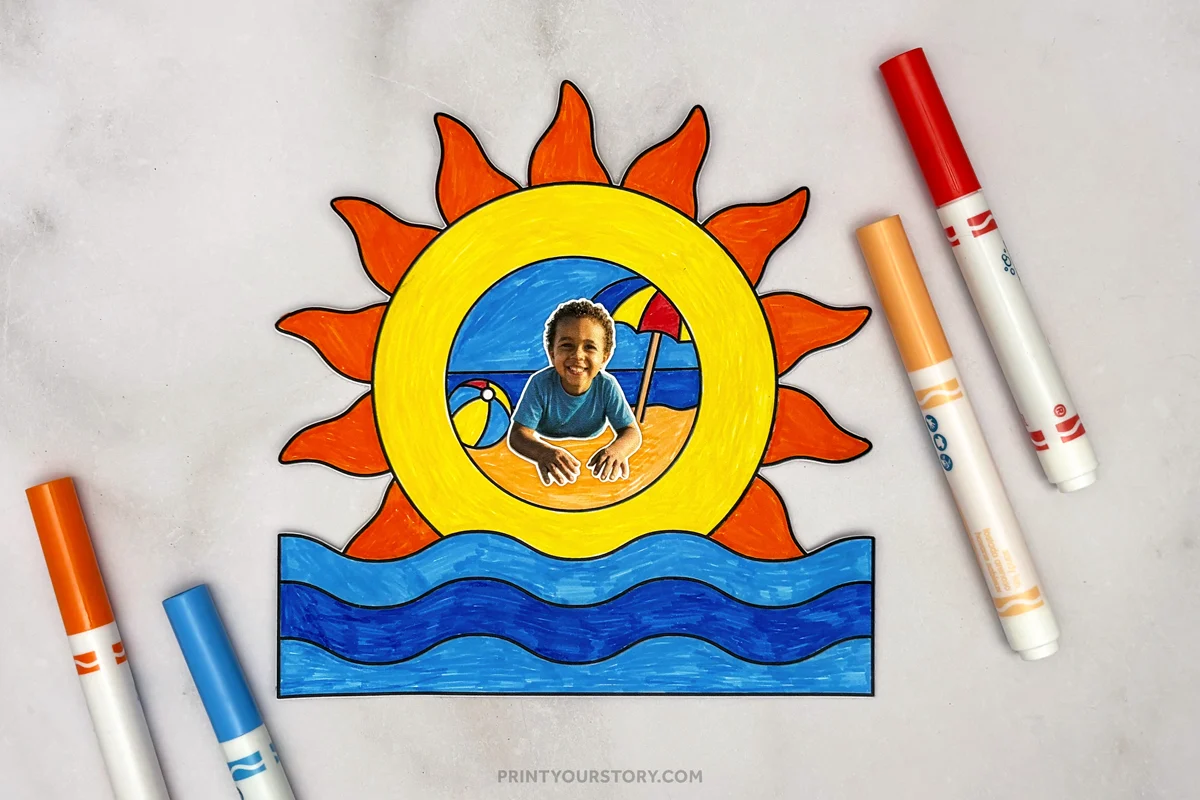 Summer photo frame craft featuring a bright sun, ocean waves, and a beach scene with a child's photo attached in the center, displayed with colorful markers on a gray background.