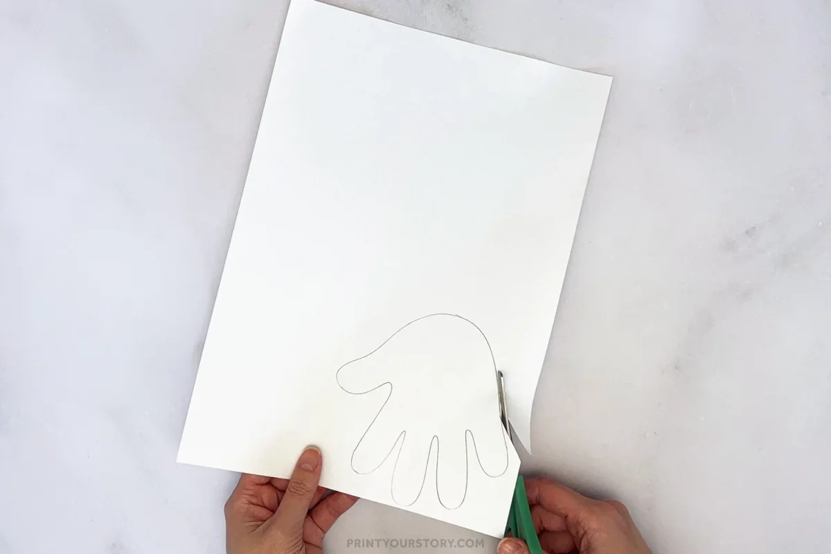 Cutting out a traced handprint on white paper for a bunny craft