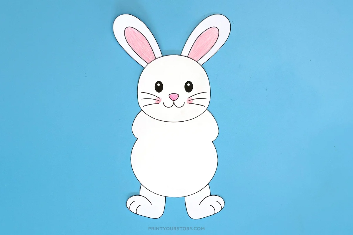 Cut-out Easter bunny craft with pink ears and a smiling face on a blue background
