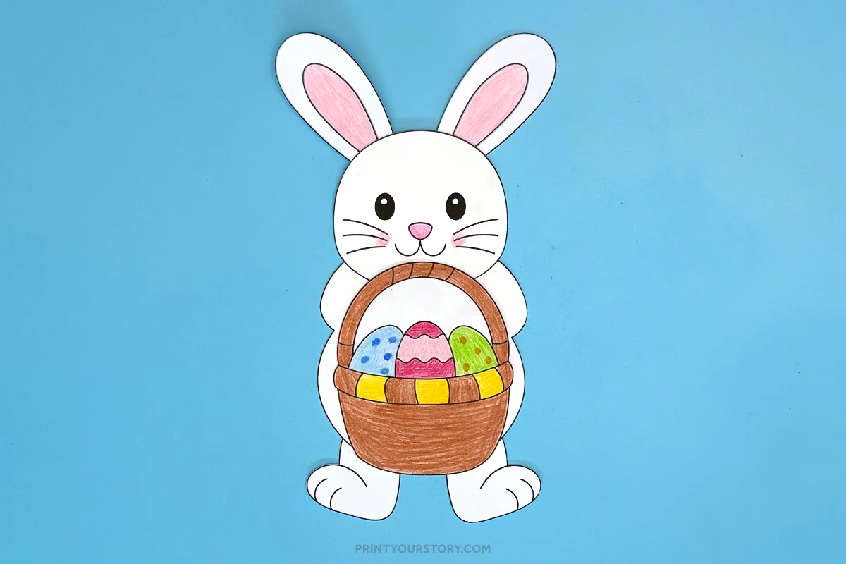 Paper Easter bunny craft holding a basket of decorated eggs on a blue background