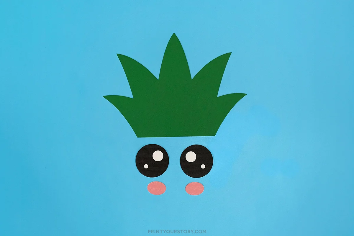 Pineapple paper plate craft template pieces with green cardstock leaves, kawaii eyes, and pink cheeks ready to be glued onto the finished pineapple craft.