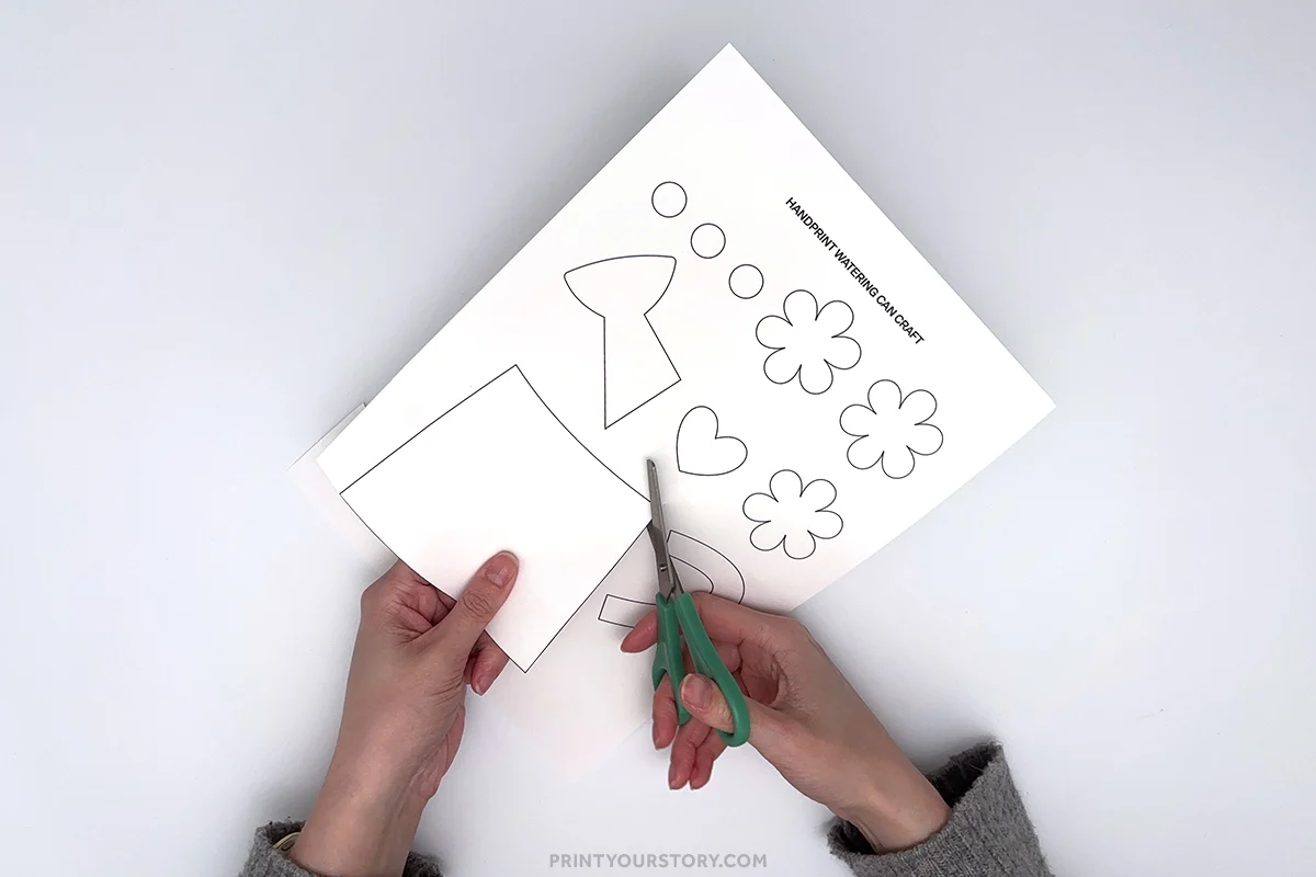 Cutting out a watering can template for a handprint spring craft