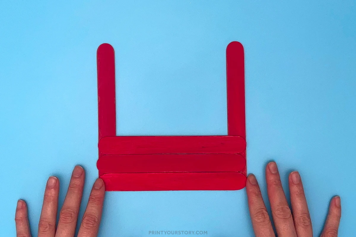 Red popsicle sticks arranged into the base and sides of a Father’s Day toolbox craft
