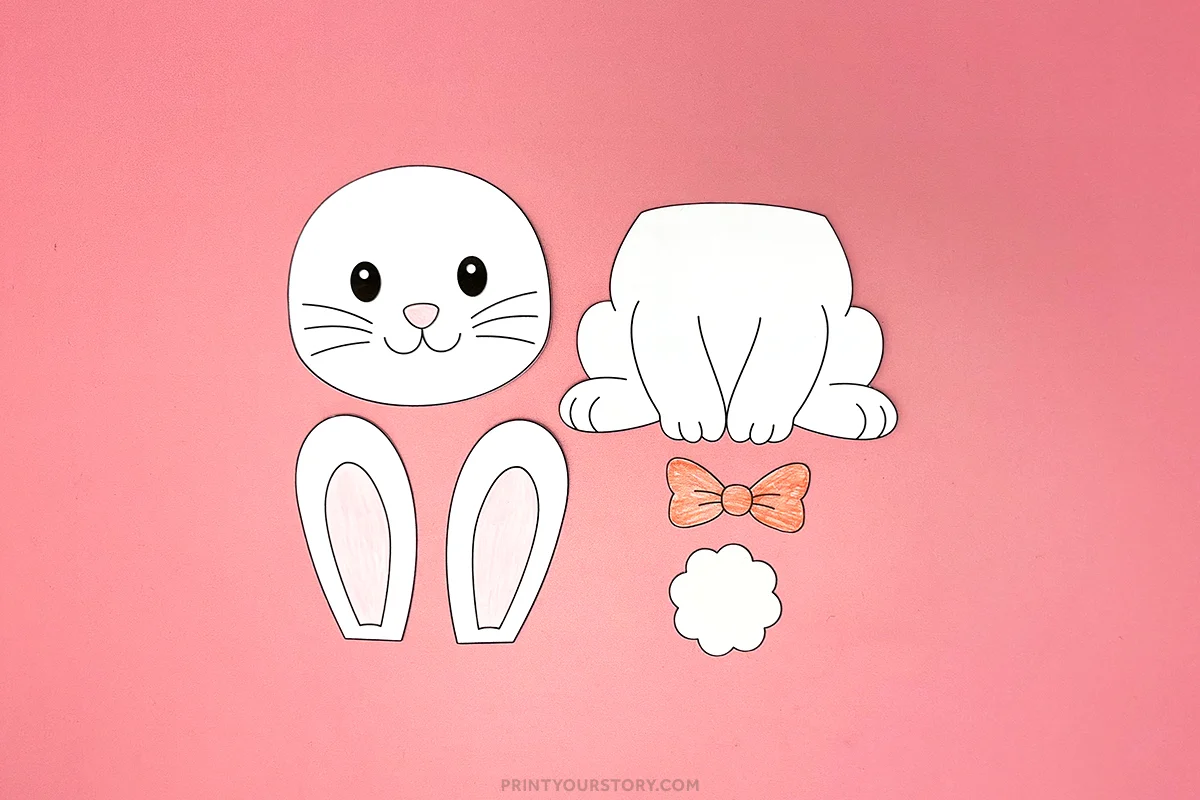 Cut-out bunny craft pieces with head, body, ears, bow tie, and tail on a pink background