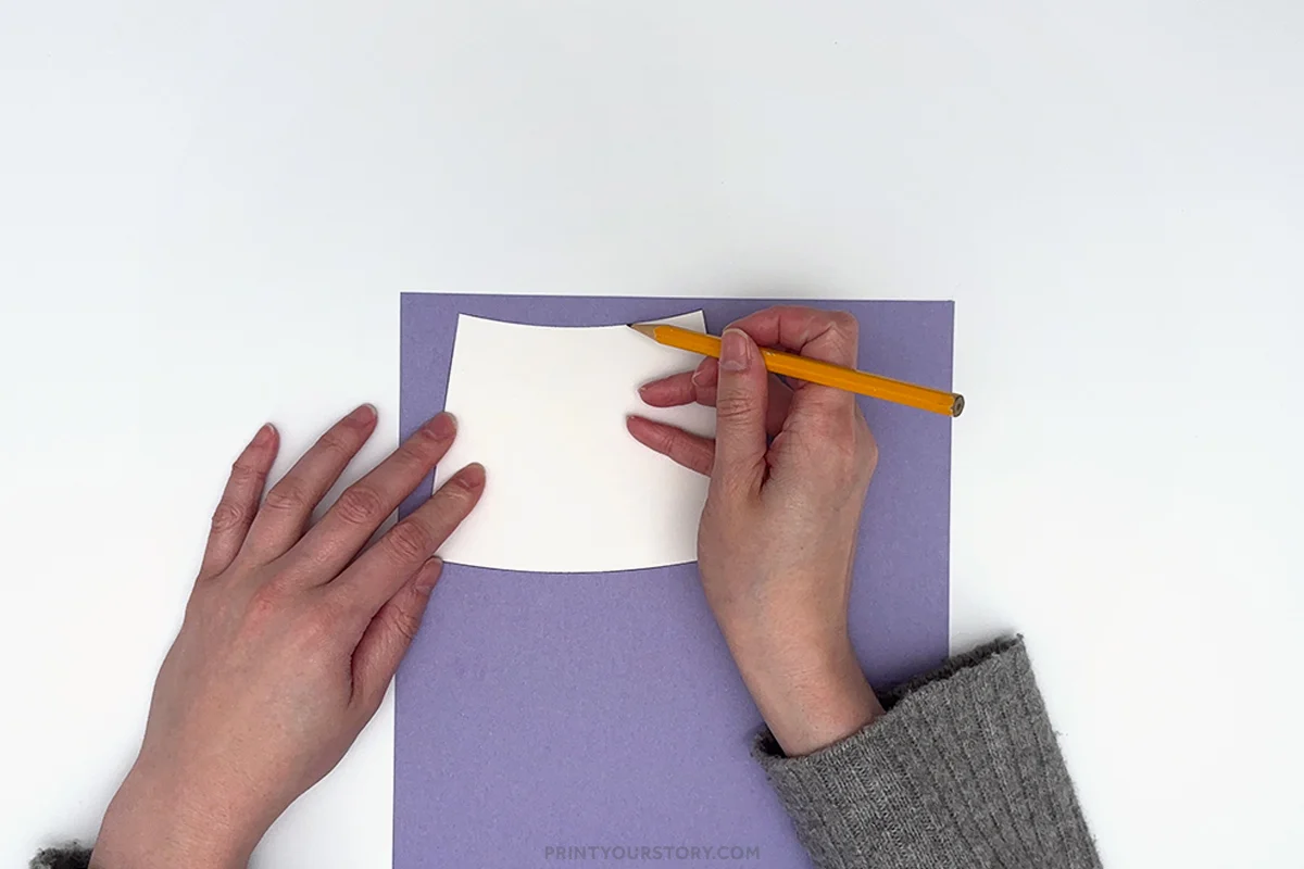 Tracing a curved white paper template onto purple paper for a watering can craft