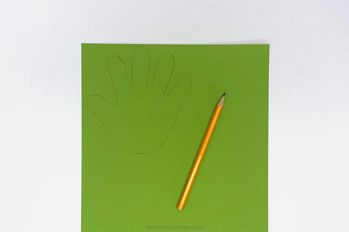 Hand outline traced on green paper with a pencil for a handprint watering can craft
