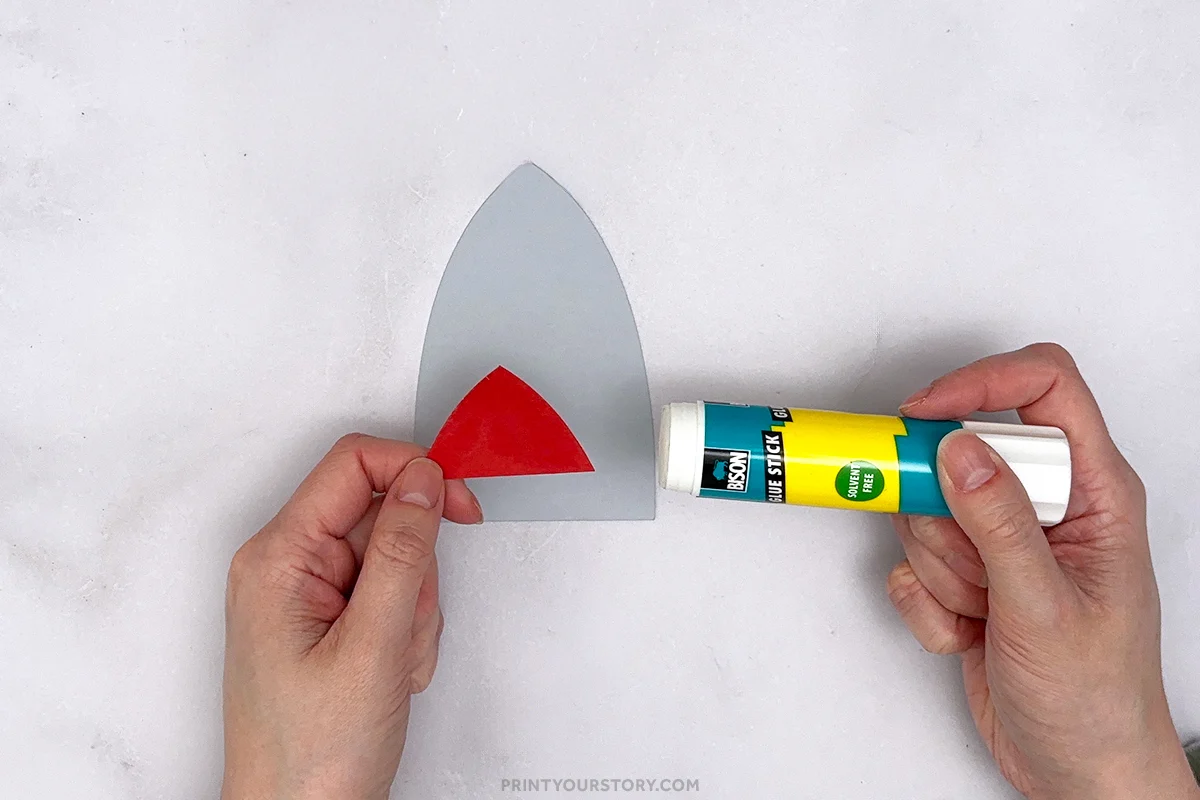Hands glue a red paper window onto