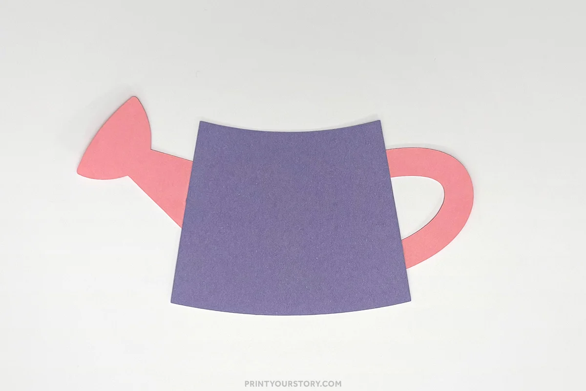 Purple and pink paper watering can craft cutout on a white background