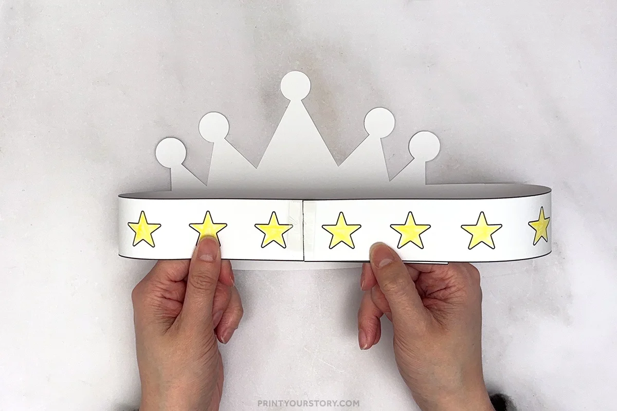 Hands holding a printable birthday crown headband with yellow stars and crown points