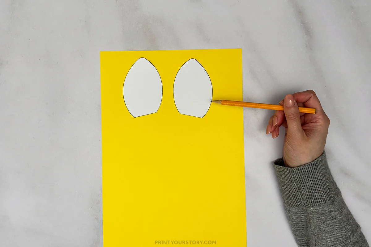 Tracing giraffe ear templates onto yellow paper for a paper plate craft