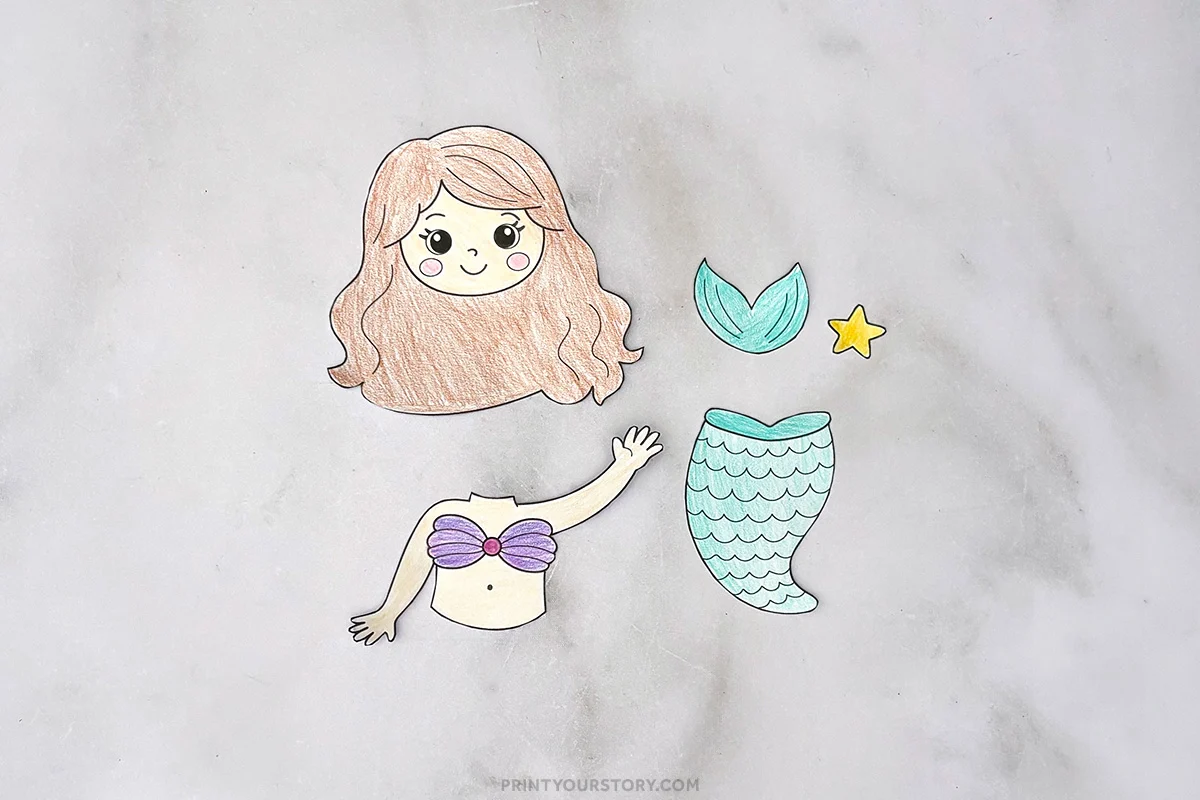 Cut-out colored paper pieces for a mermaid craft, including head, torso, tail, fin, and star.