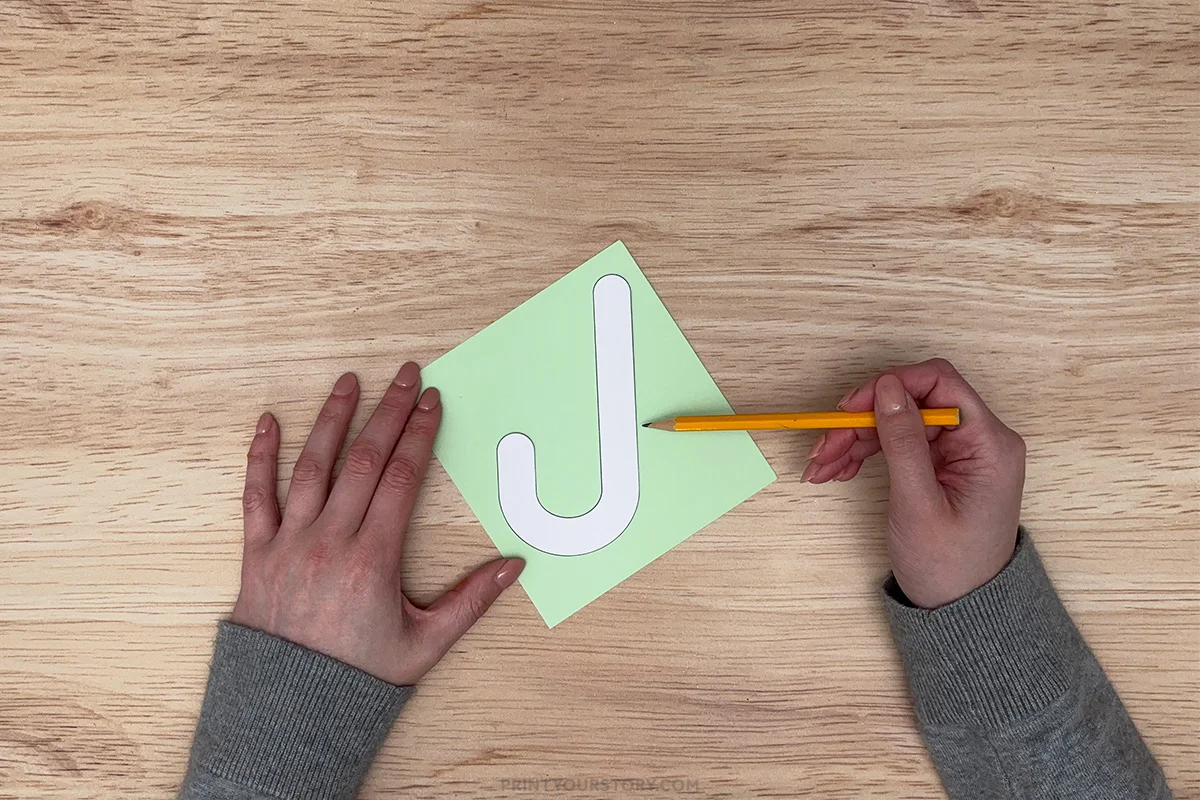Tracing an umbrella handle template onto green paper with a pencil