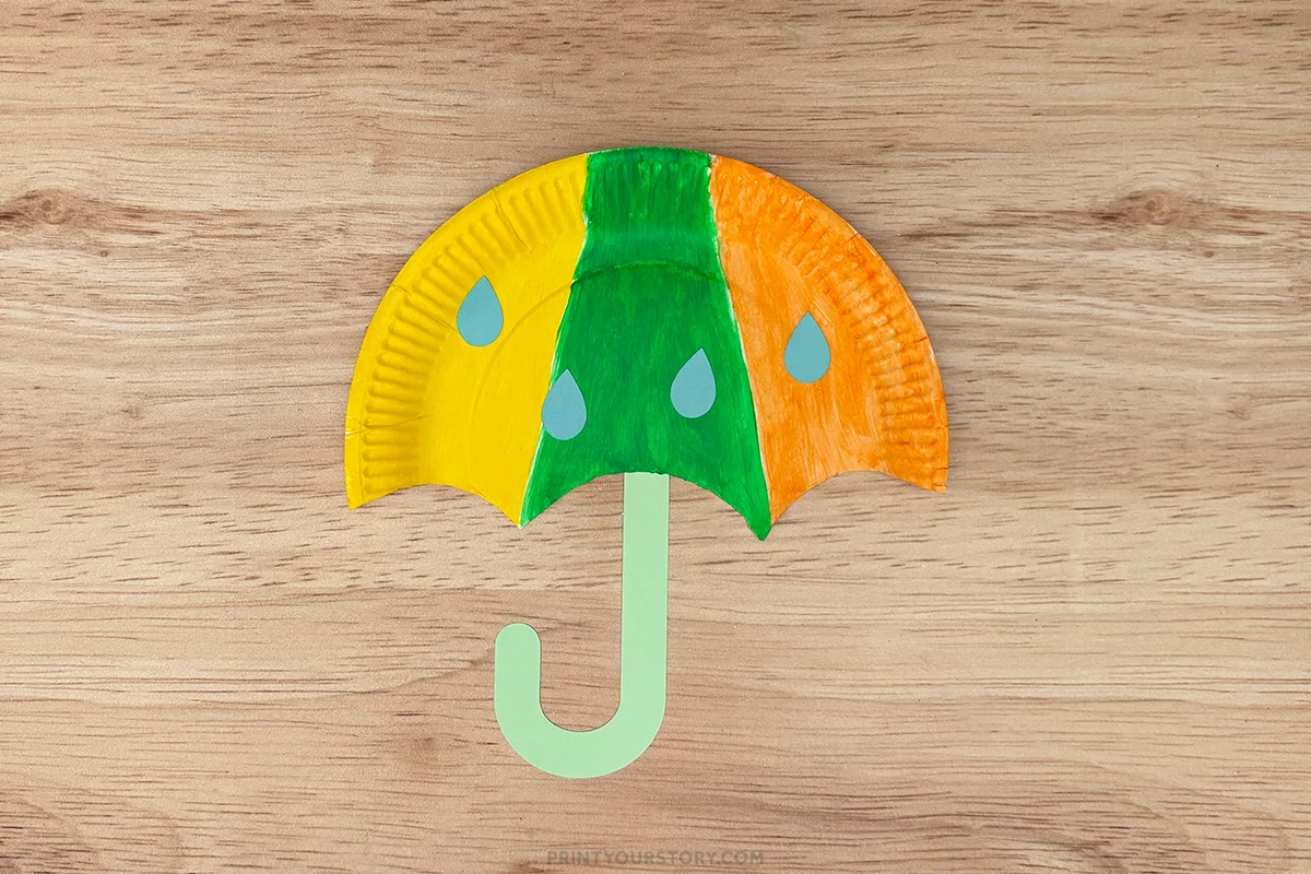 Finished umbrella paper plate craft with yellow, green, and orange canopy, raindrops, and green handle