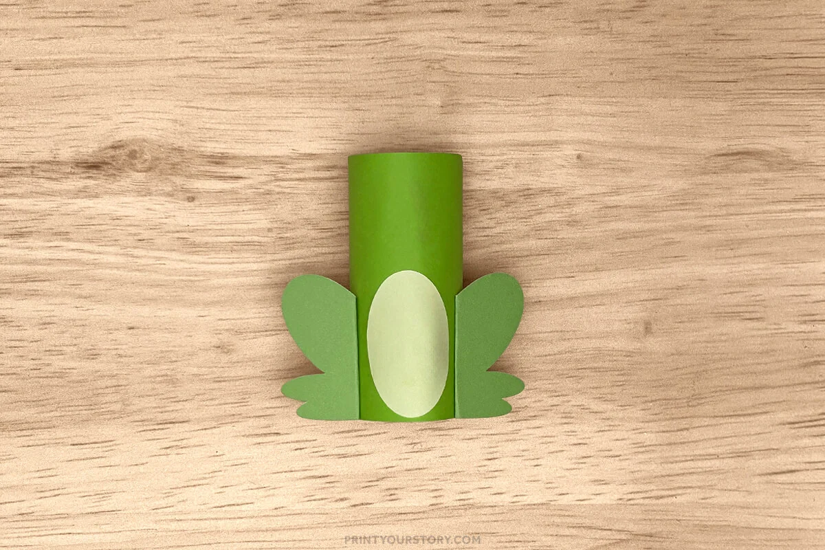 Green toilet paper roll frog craft with legs and a light green belly attached