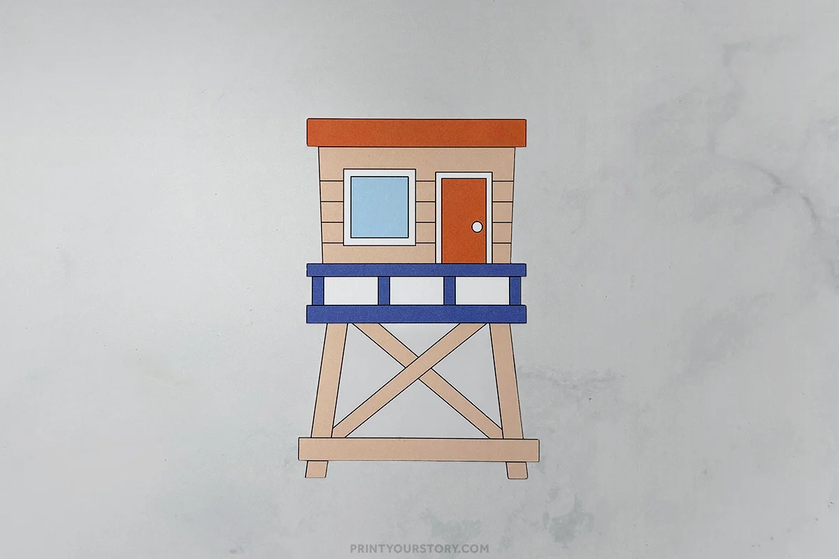 Paper lifeguard tower craft with orange roof, blue railing, and crossed support beams