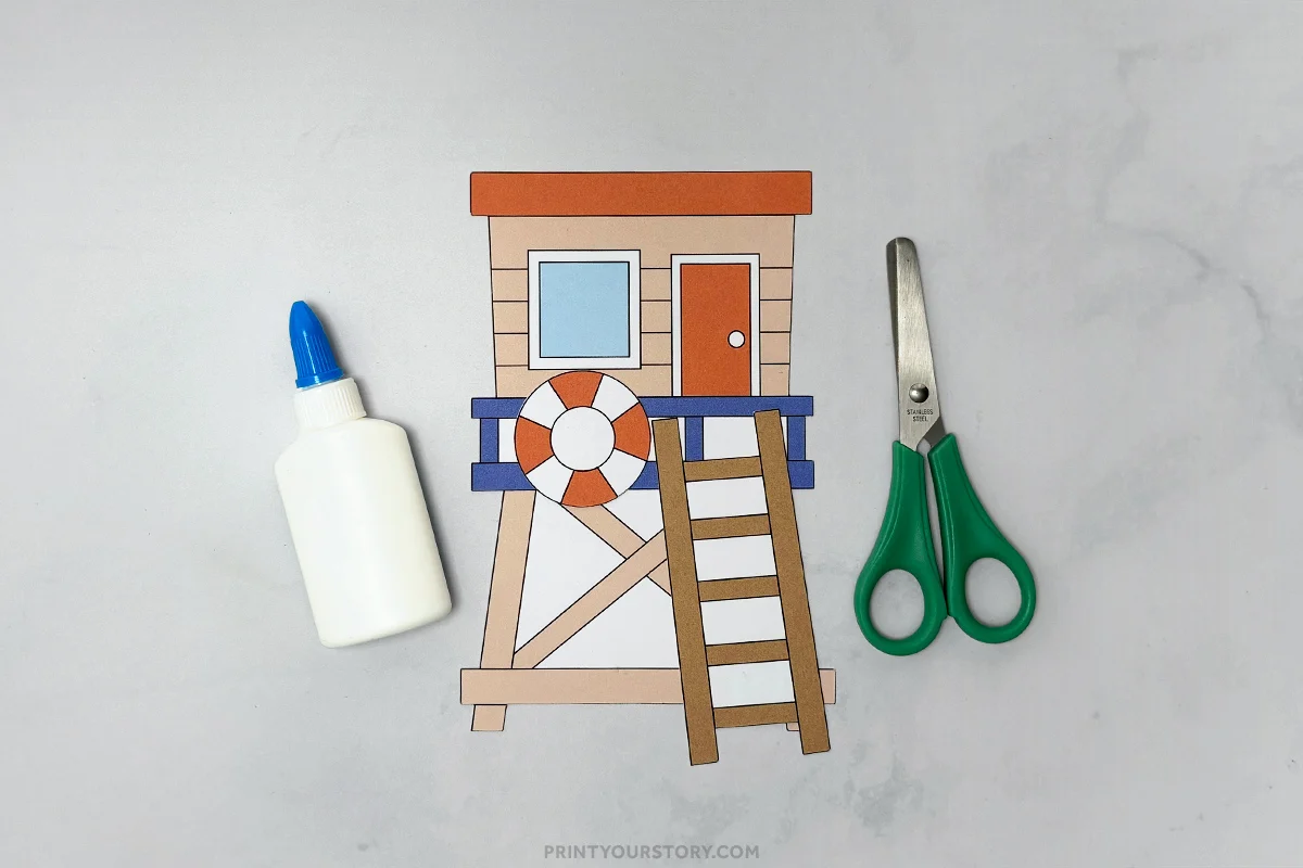 Paper lifeguard tower craft with glue bottle and green scissors on a gray surface