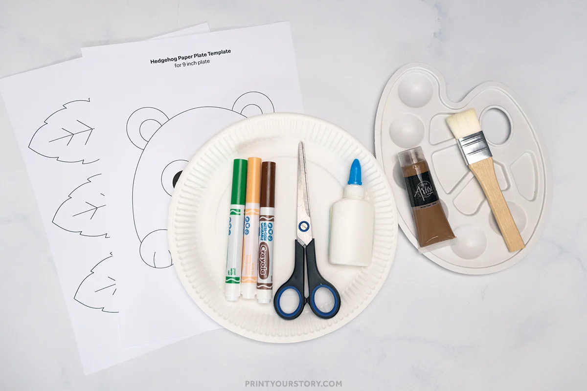 Materials for paper plate hedgehog craft: template pages, paper plate, markers, scissors, glue, paint, palette, and brush