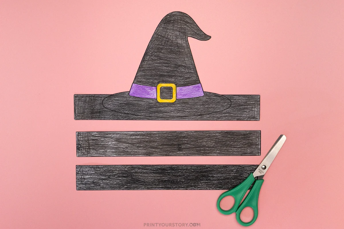 Cut out witch hat headband craft pieces with green scissors on a pink background