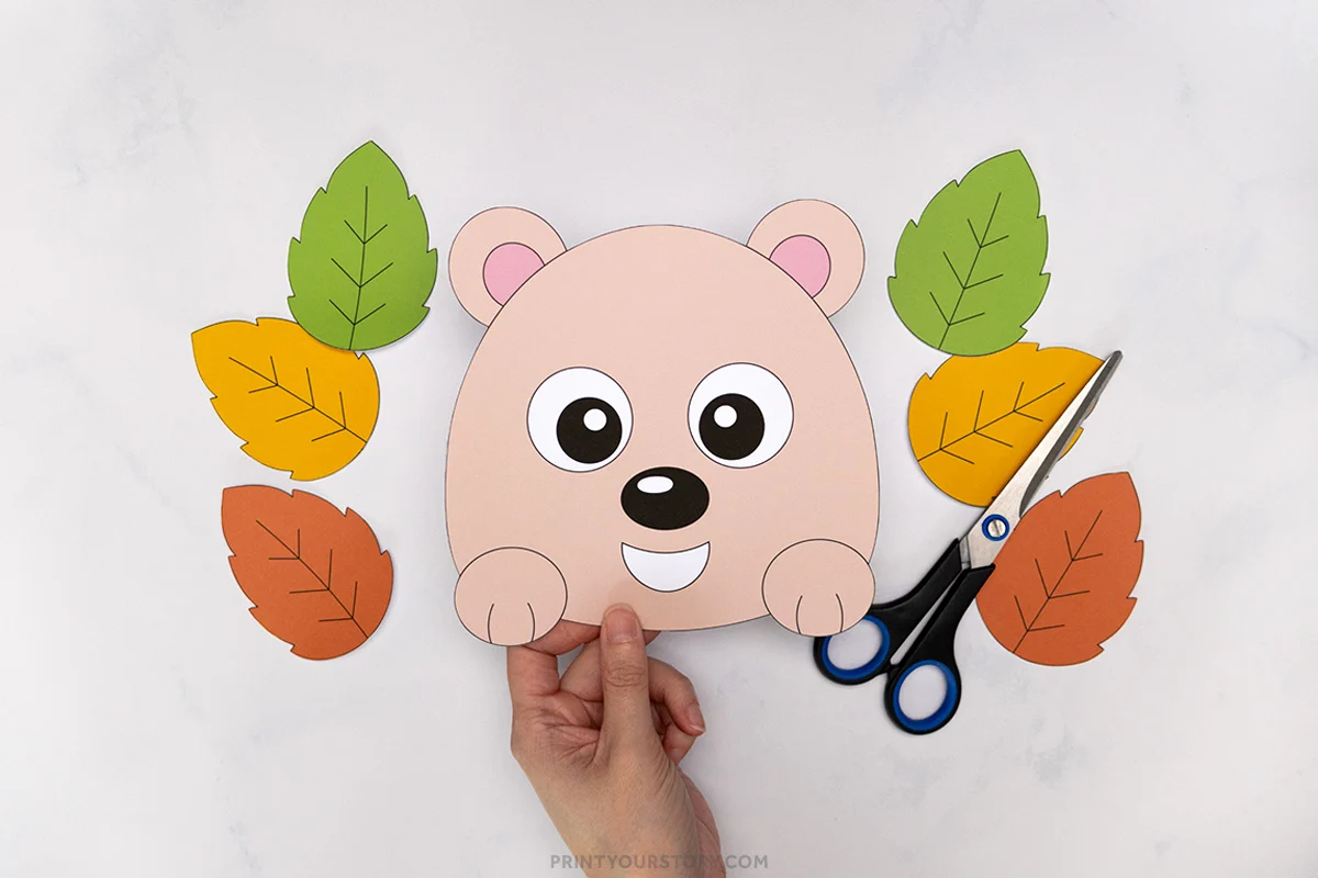 Paper hedgehog craft face with cutout fall leaves and scissors on a white background