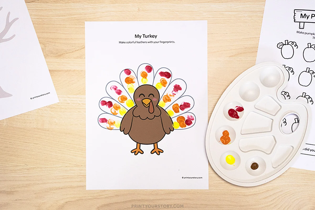 Turkey finger painting printable with colorful fingerprint feathers and a paint palette on a table