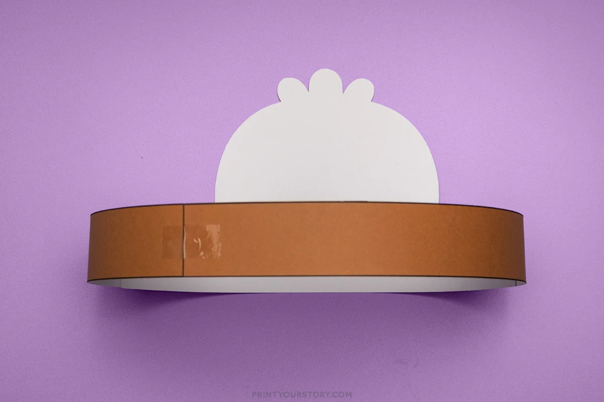 Brown paper turkey headband band taped into a circle with the white turkey face piece attached behind it