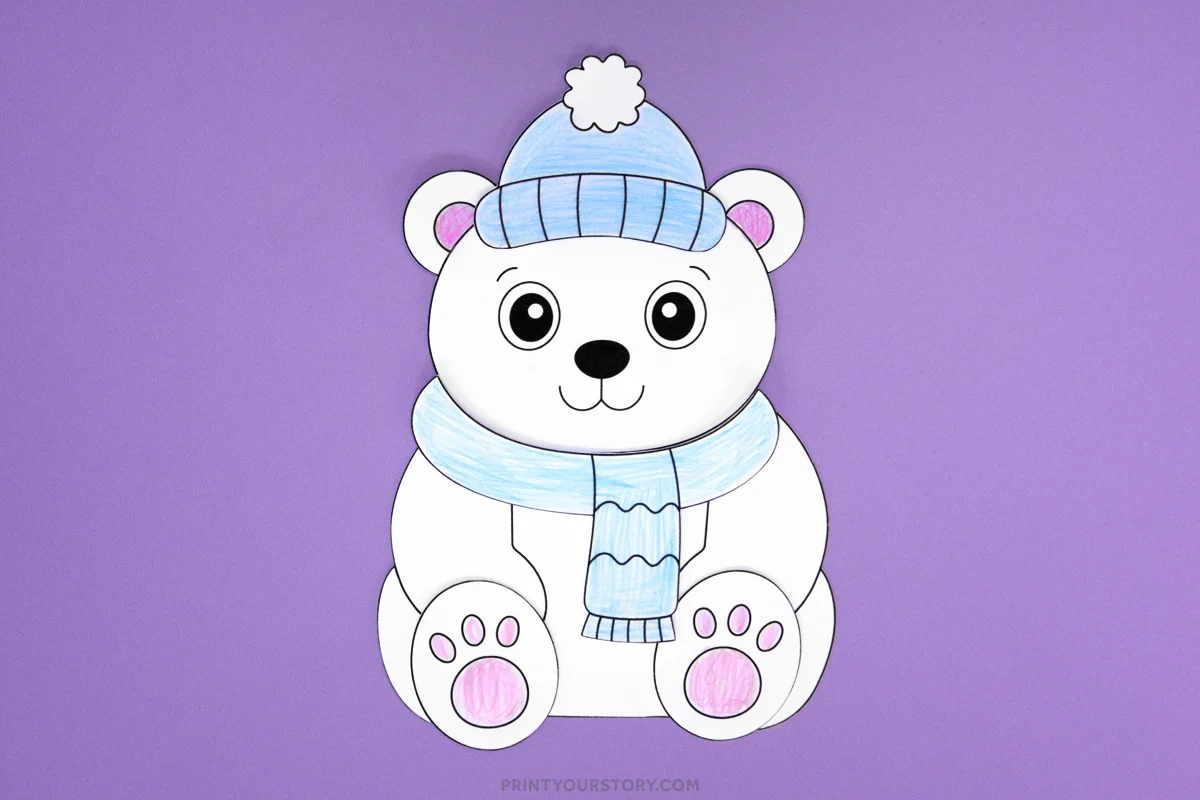 Completed polar bear craft with a blue hat and scarf, pink ears and paw pads, on a purple background