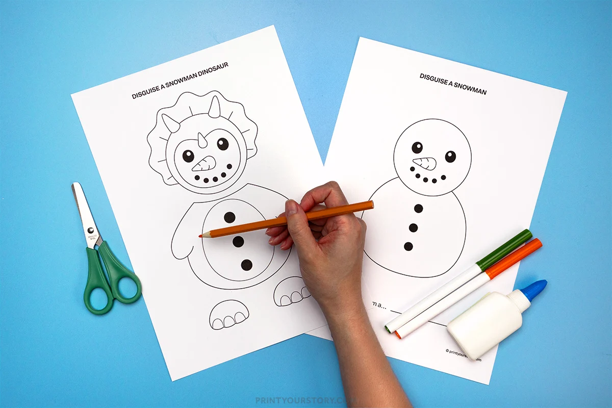 Hand drawing on disguise a snowman dinosaur printable next to snowman worksheet, scissors, markers, and glue
